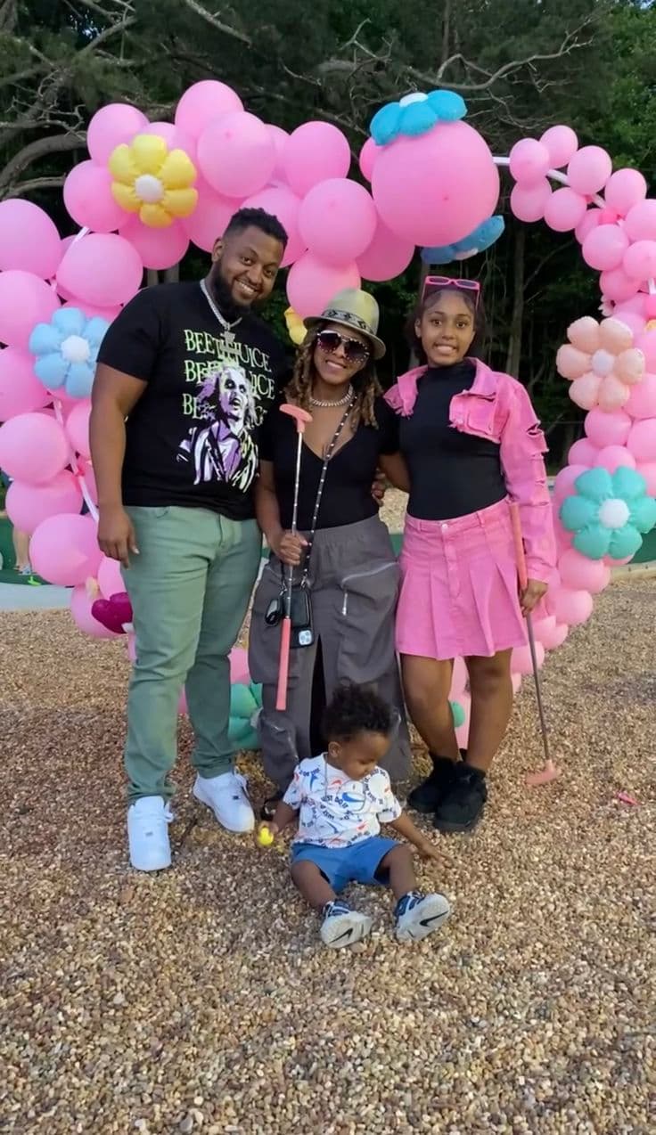 Family celebrating a birthday under the pink balloon arch