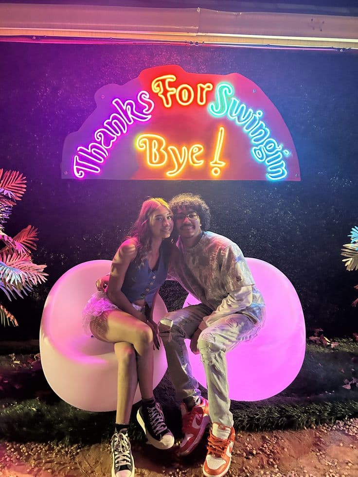 Couple under the Thanks For Swingin By neon sign